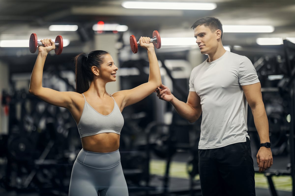 Personal trainer helping client with strength training