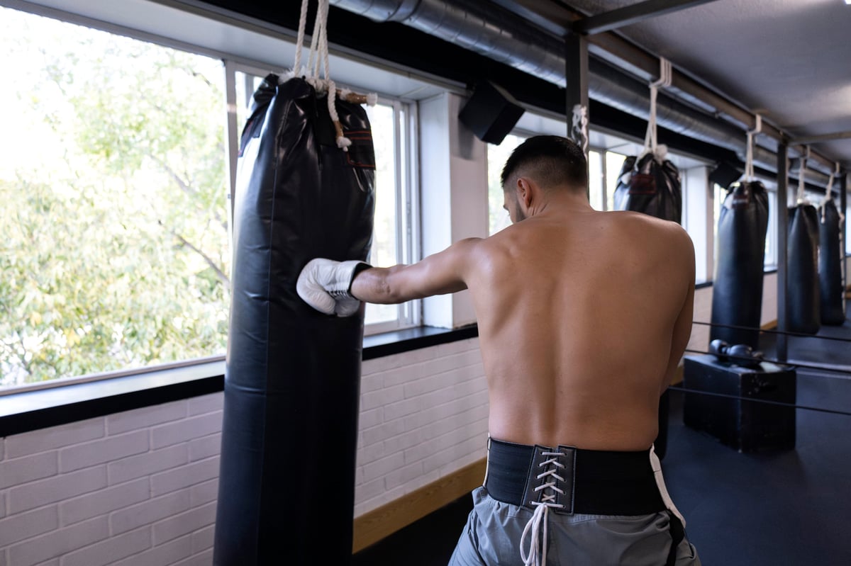 Male athlete punching heavy bag during boxing workout in a gym